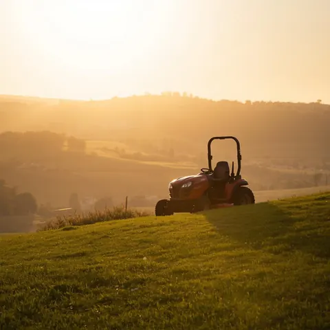 Tractor de tuns iarba pe un gazon la apus